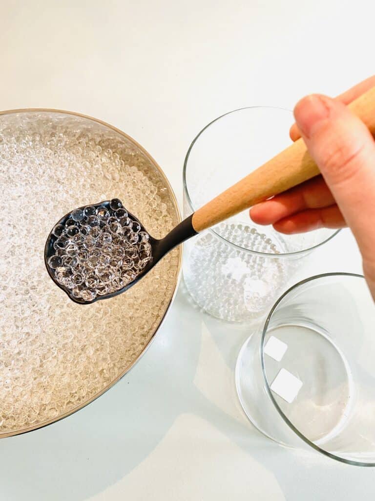 spooning water beads into vase