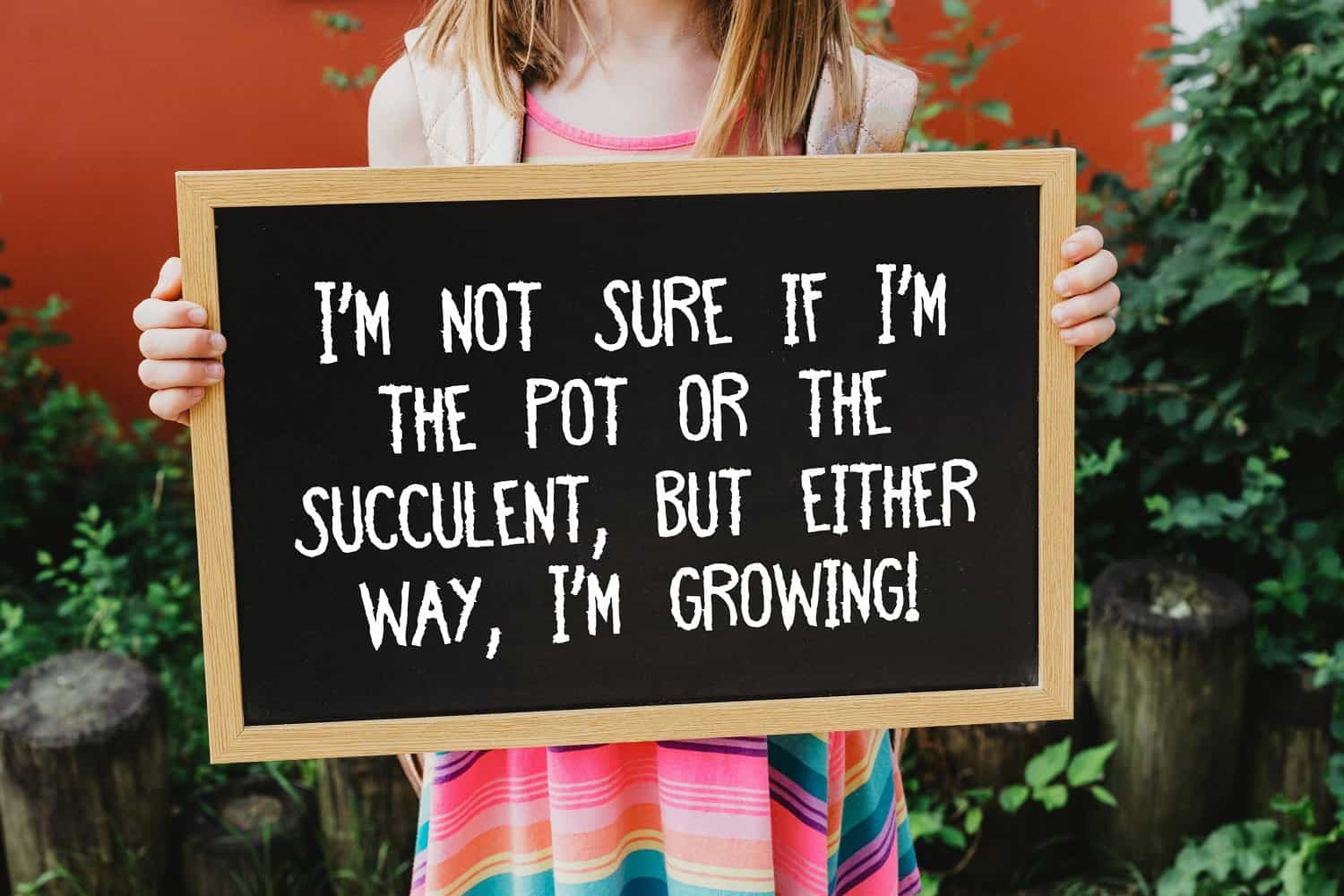 girl holding chalkboard with succulent pun in front of plants